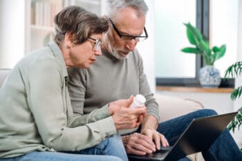 Senior couple, sit down on couch and look at medication and laptop. Image for Blog Medicare's Role in Your Financial Future